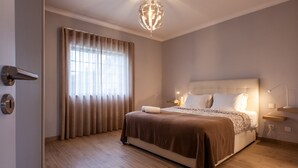 Un dormitorio moderno con una cama grande, una araña y una ventana con cortinas.