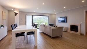 Una sala de estar moderna con comedor, sofá, chimenea y televisor montado en la pared.