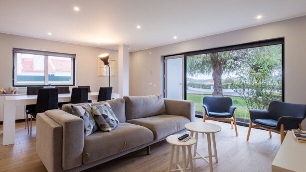 Una sala de estar moderna con un sofá, dos sillones, una mesita y un comedor con sillas y una mesa.
