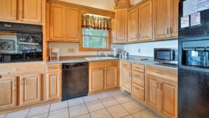 A kitchen with wooden cabinets, a dishwasher, a sink, a window with a valance, and a refrigerator.