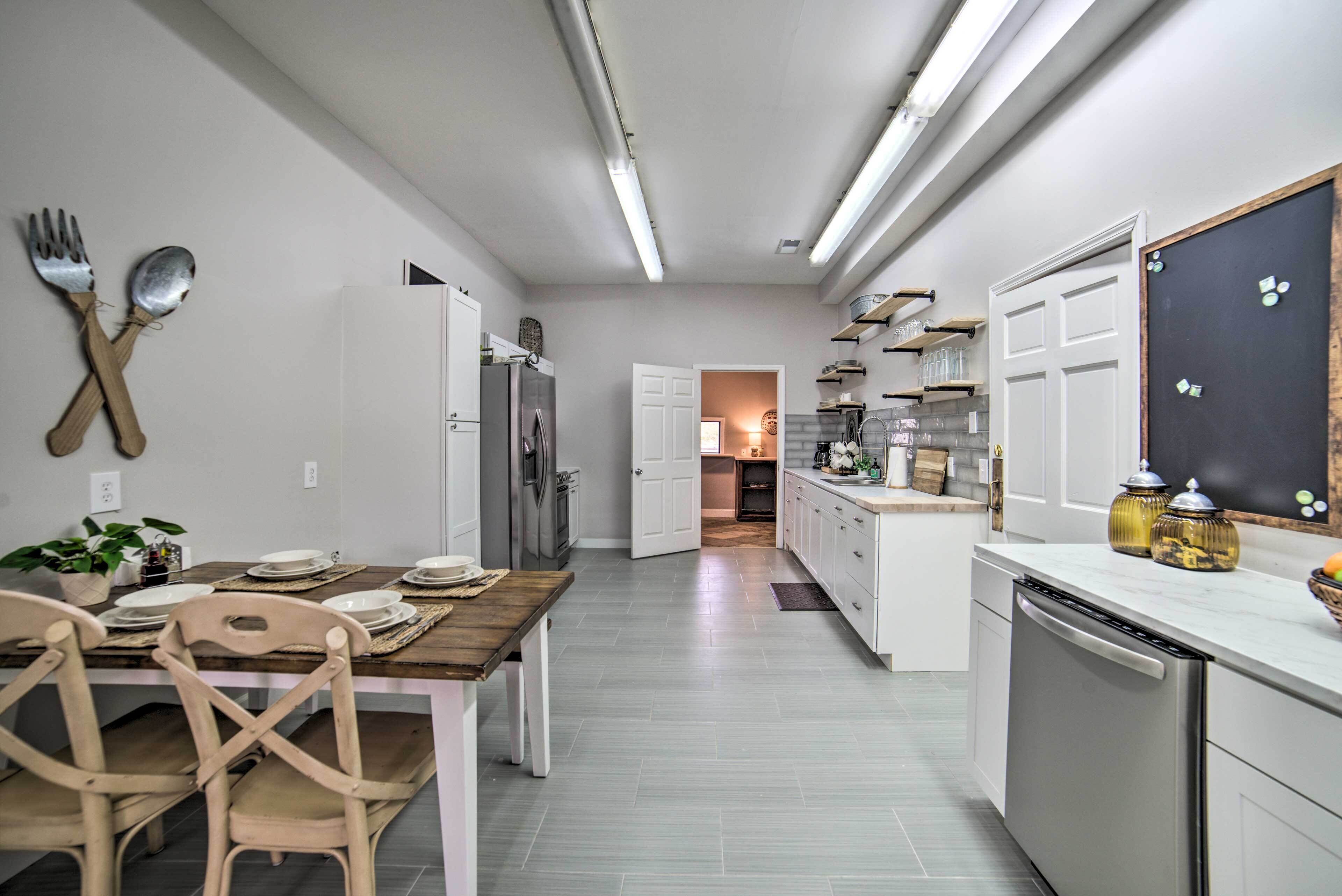 Une cuisine moderne avec des meubles blancs, une table à manger en bois et un réfrigérateur.