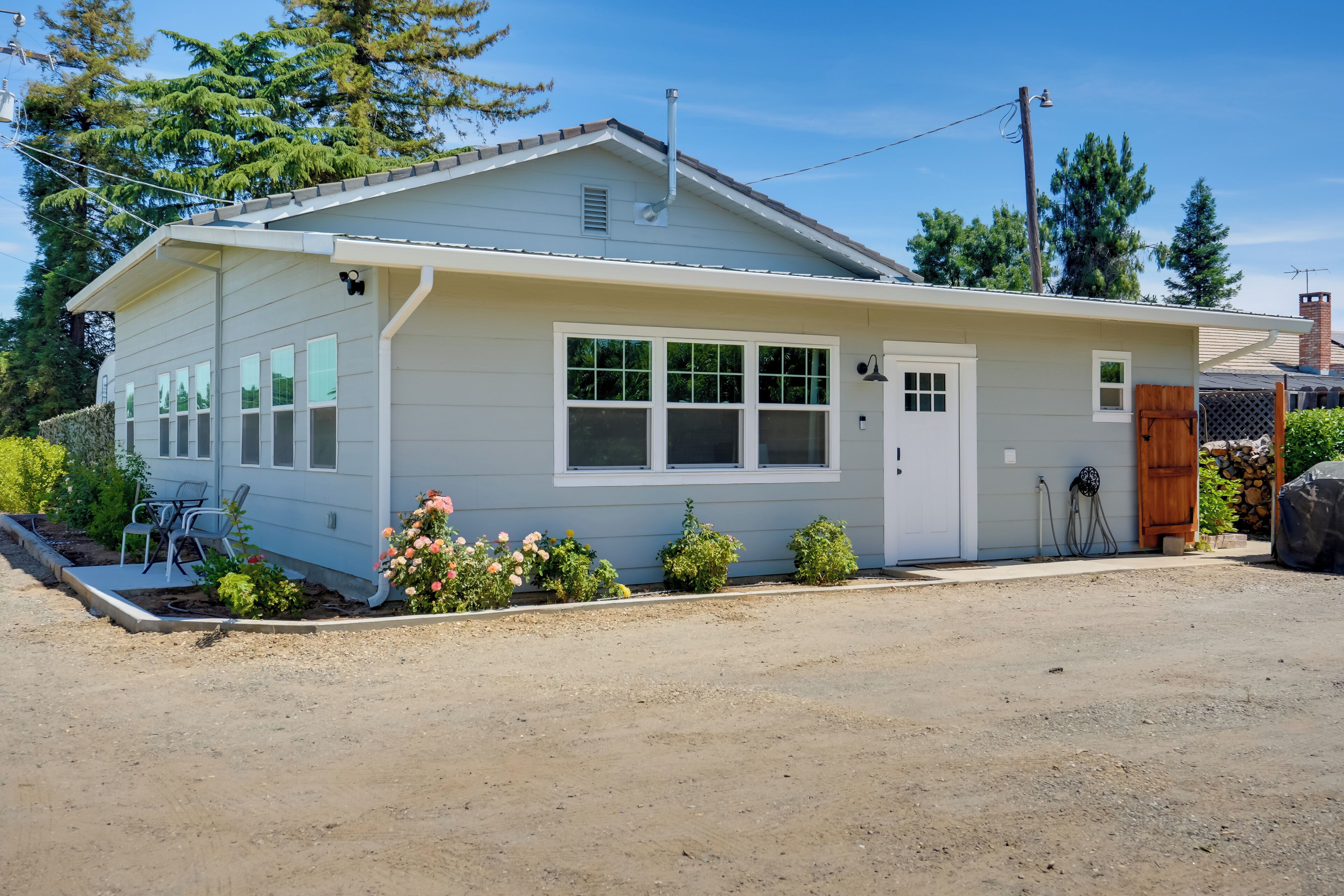 Une maison de plain-pied avec un porche à l’avant, un garage et un petit jardin fleuri.
