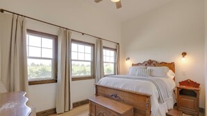 Ein Schlafzimmer mit einem großen Bett, zwei Nachttischen, einer Holzbank und einem Fenster mit Vorhängen.