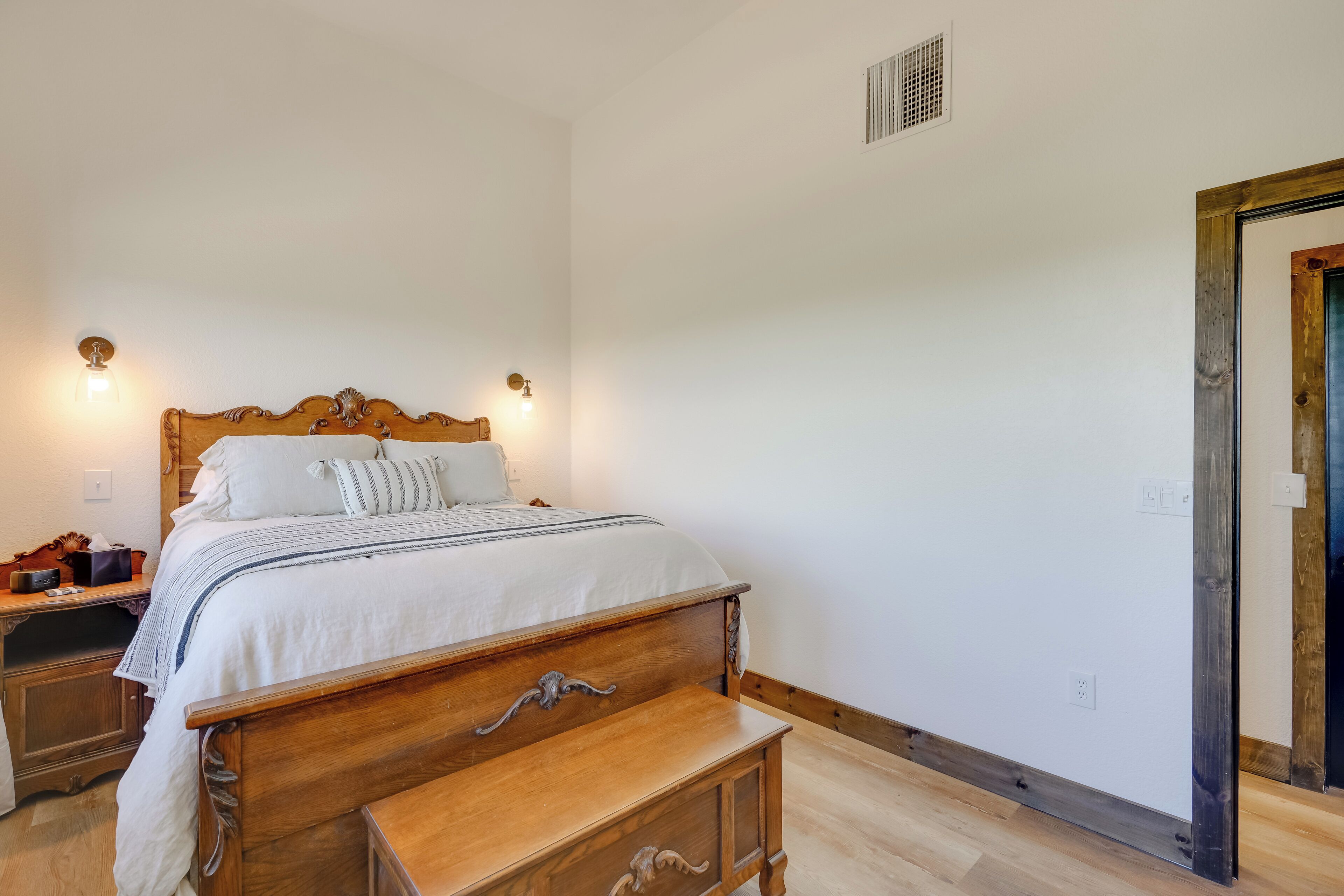 Une chambre à coucher avec un lit en bois, des tables de chevet et un banc en bois.