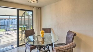A glass-top dining table with wicker chairs, a glass vase with lemons, and a ceiling light fixture. - Bright Venice Home w/ Yard < 4 Miles to Beach! (Venice)