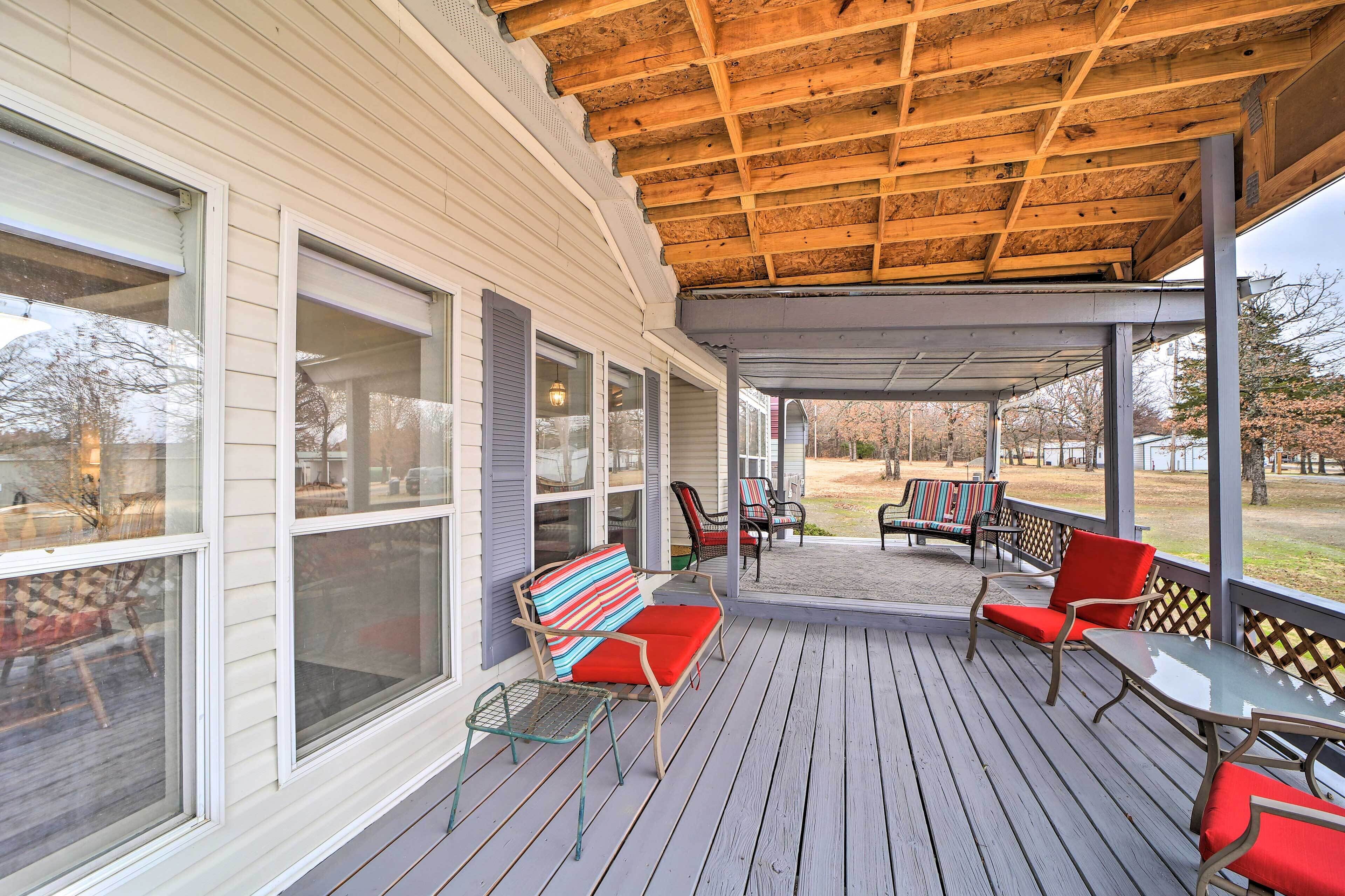 A covered porch with wooden flooring, a bench with a striped cushion, and a table with chairs.