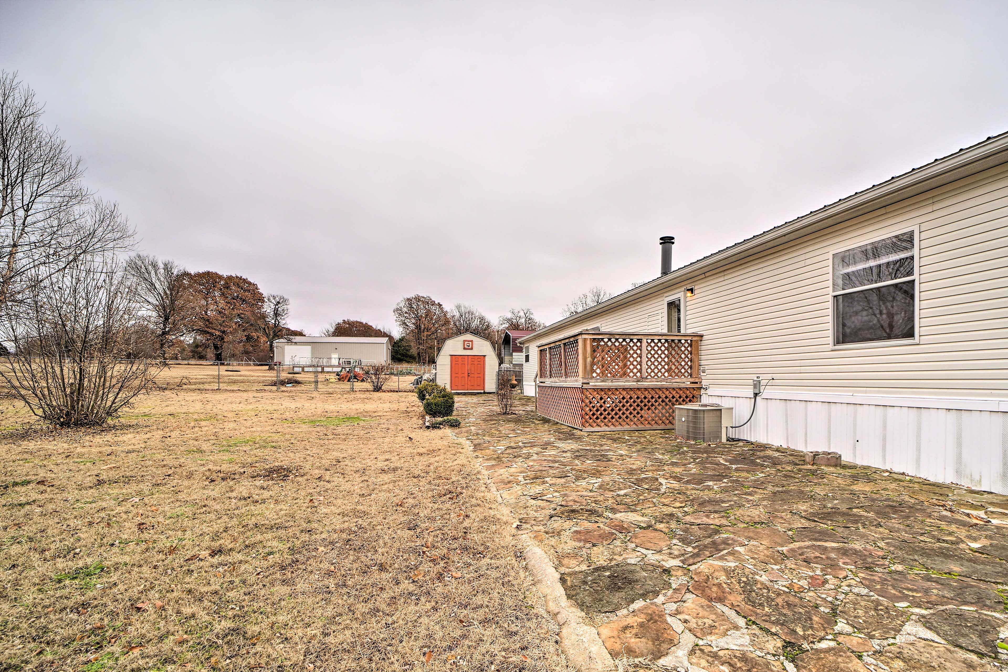 A house with a stone patio, a wooden deck, and a small shed.