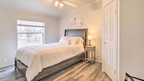 A bedroom with a bed, a nightstand, a ceiling fan, a window, and a door. - Eufaula Escape w/ Deck - Steps to Lake! (Eufaula)