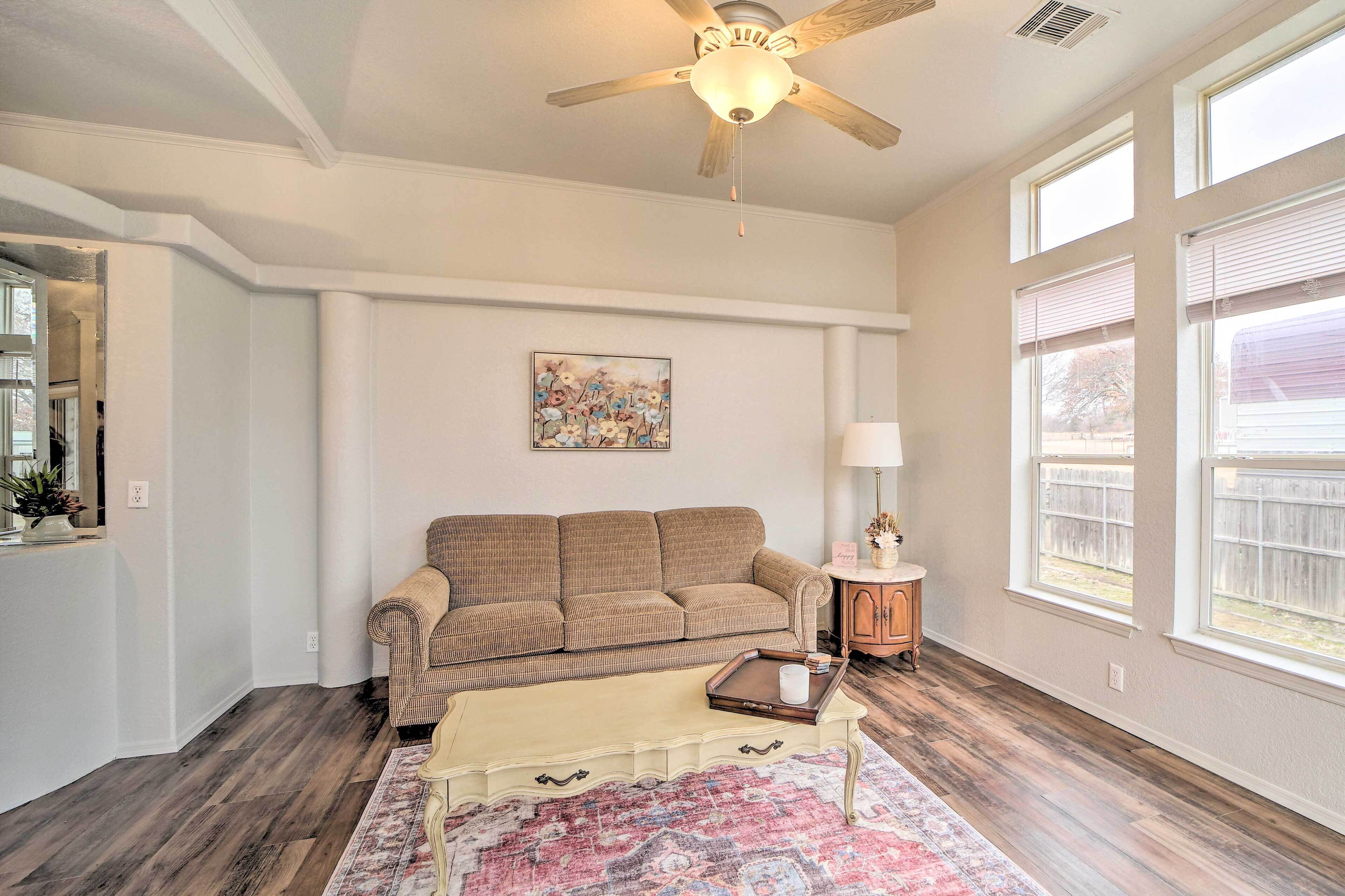 A living room with a beige sofa, a coffee table, and a ceiling fan.