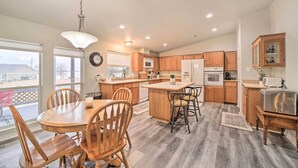 A spacious kitchen with wooden cabinets, a central island, and a dining area with wooden chairs. - Eufaula Escape w/ Deck - Steps to Lake! (Eufaula)