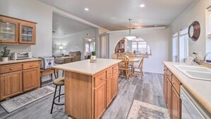 A spacious kitchen with wooden cabinets, a central island, and a dining area with a chandelier. - Eufaula Escape w/ Deck - Steps to Lake! (Eufaula)