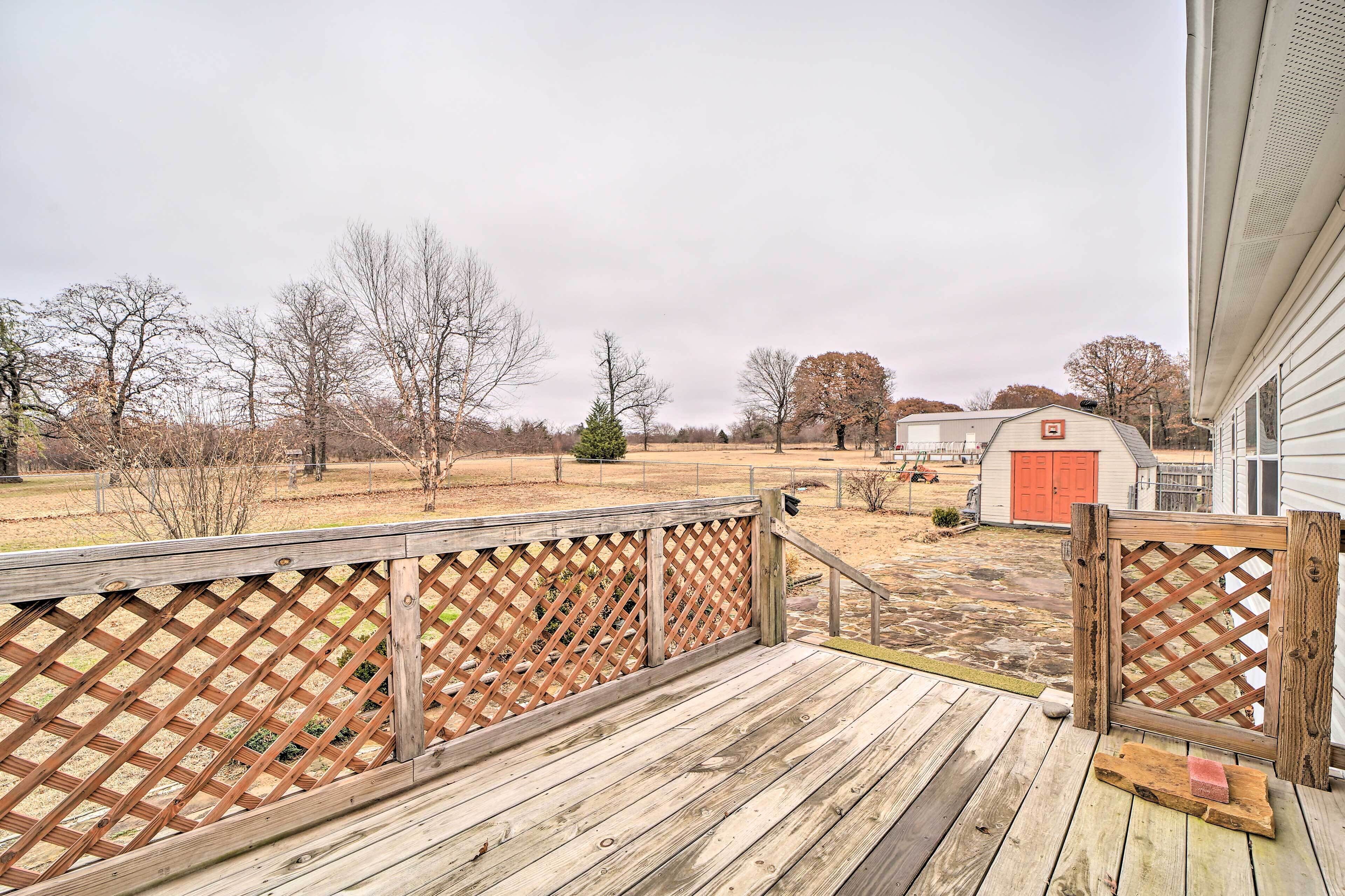 A wooden deck with a lattice fence, a small shed, and a red door in the background.
