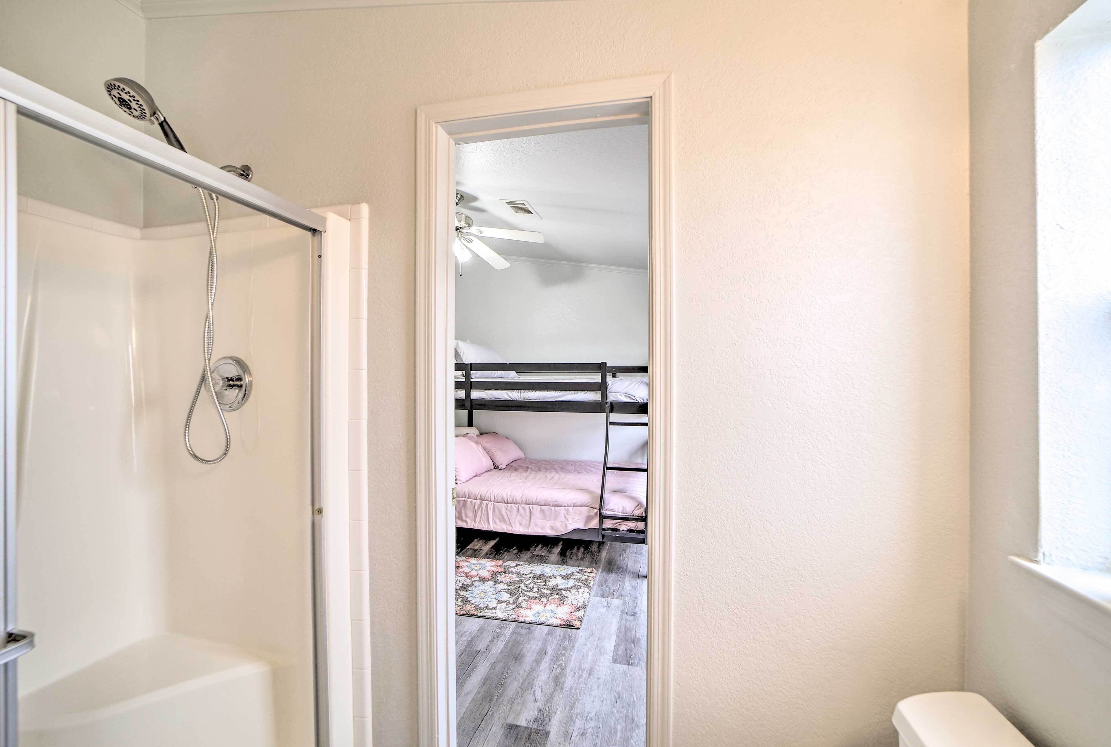 Un bagno con doccia e vasca, e un letto a castello nella stanza adiacente.