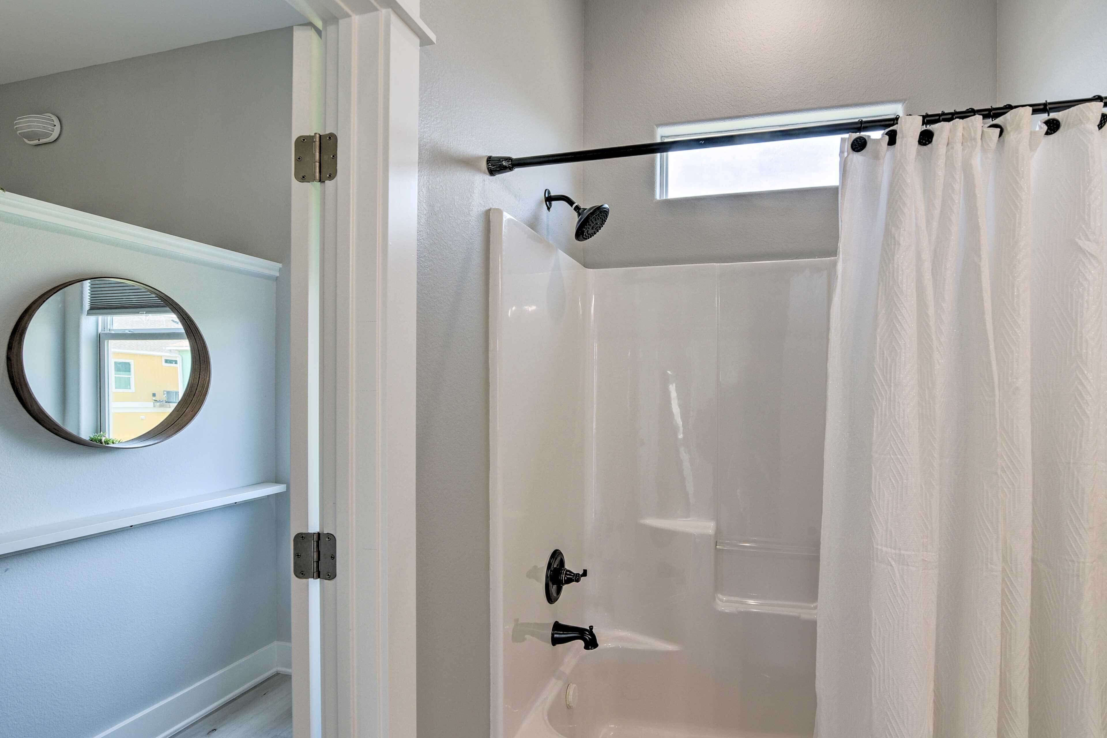 A bathroom with a glass-enclosed shower, a white bathtub, and a white shower curtain.