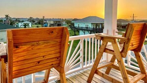 Terraza de madera con dos sillas, con vistas a una zona residencial con casas y un muelle.