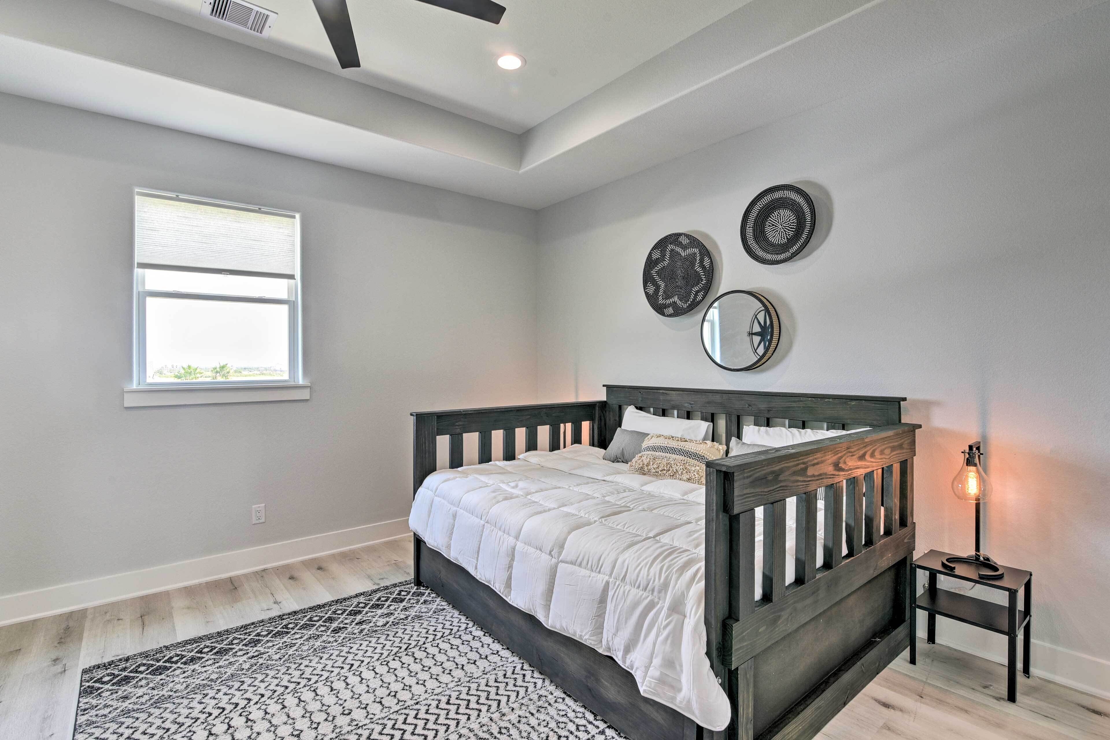 A bedroom with a bed, a nightstand, a floor lamp, a window, and decorative plates on the wall.