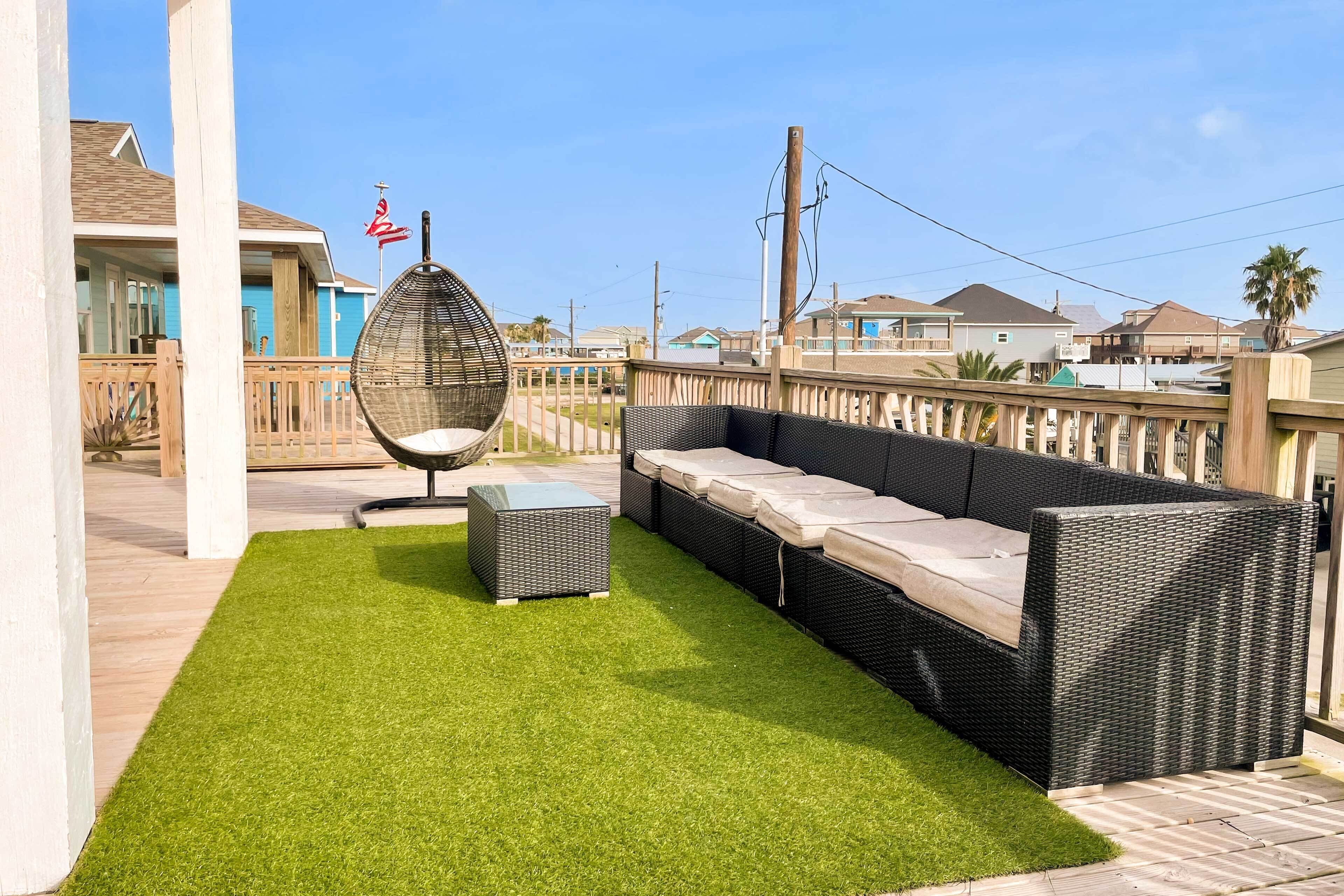 A patio area with a wicker sofa, a wicker chair, and a small table.