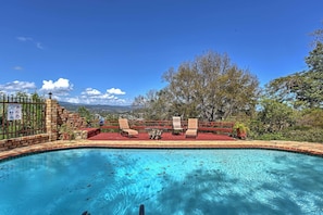 A swimming pool with a view of mountains, a fenced area with chairs, and a sign indicating a no swimming zone.