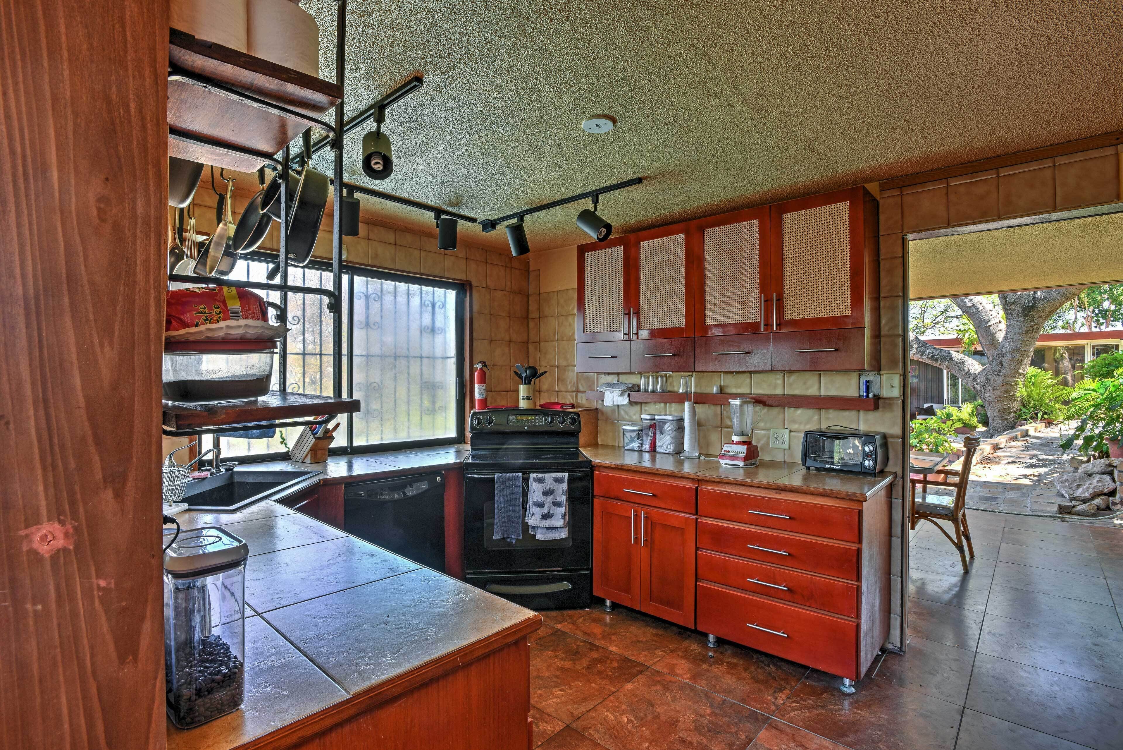 A kitchen with a stove, oven, and cabinets. There is a window and a door leading to an outdoor area.