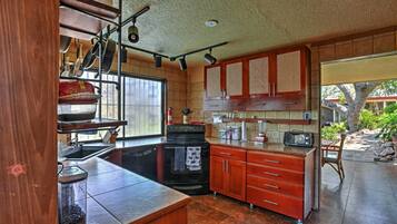 A kitchen with a stove, oven, and cabinets. There is a window and a door leading to an outdoor area.