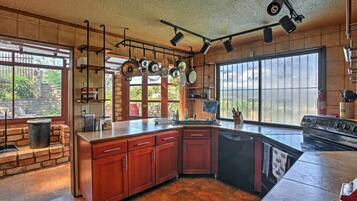 A kitchen with a large island, hanging pots, and a stove.