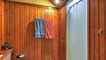 A wooden-paneled bathroom with two towels hanging on the wall, a toilet, and a shower curtain.