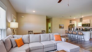 A modern living room with a sectional sofa, a coffee table, and a kitchen area with bar stools.