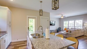 A kitchen with granite countertops, a sink, and a dining area with a table and chairs.
