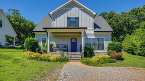 A two-story house with a front porch, a blue door, and a gravel driveway.