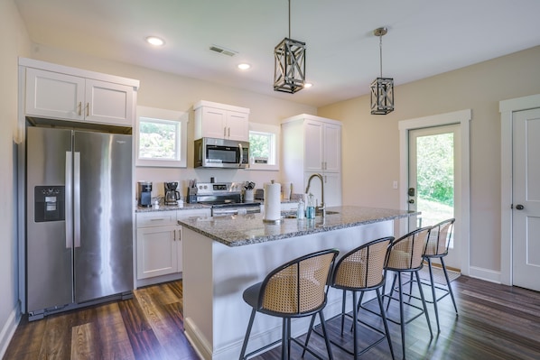 A modern kitchen with stainless steel appliances, white cabinets, and a central island with bar stools.