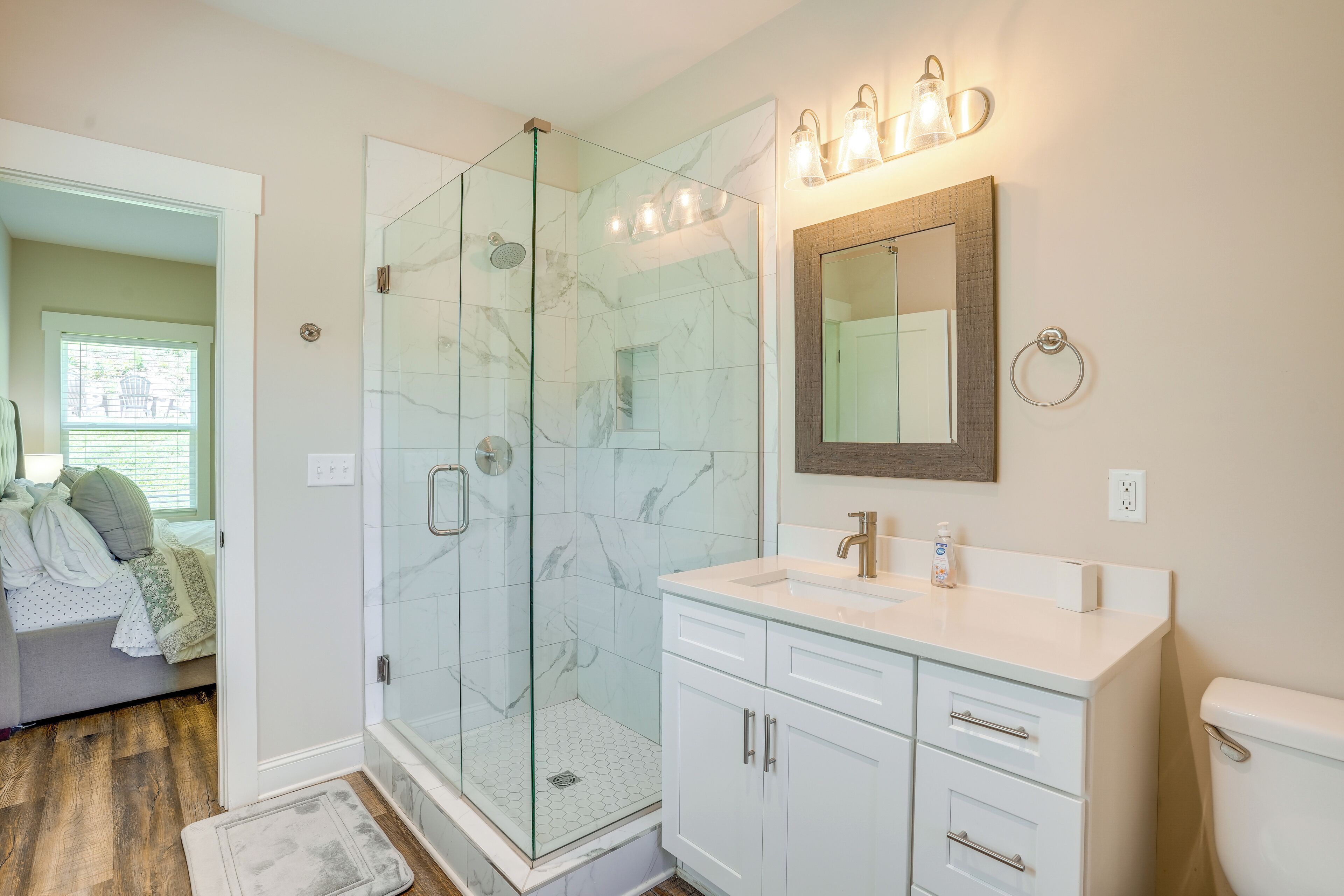 Un baño moderno con cabina de ducha de vidrio, un lavamanos blanco y un espejo grande.