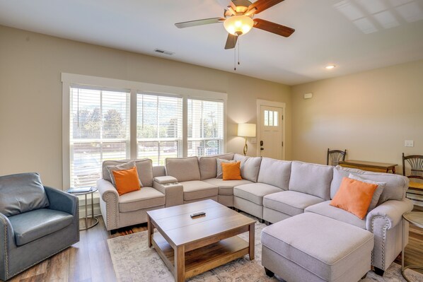 A living room with a sectional sofa, a coffee table, a leather armchair, and a ceiling fan.