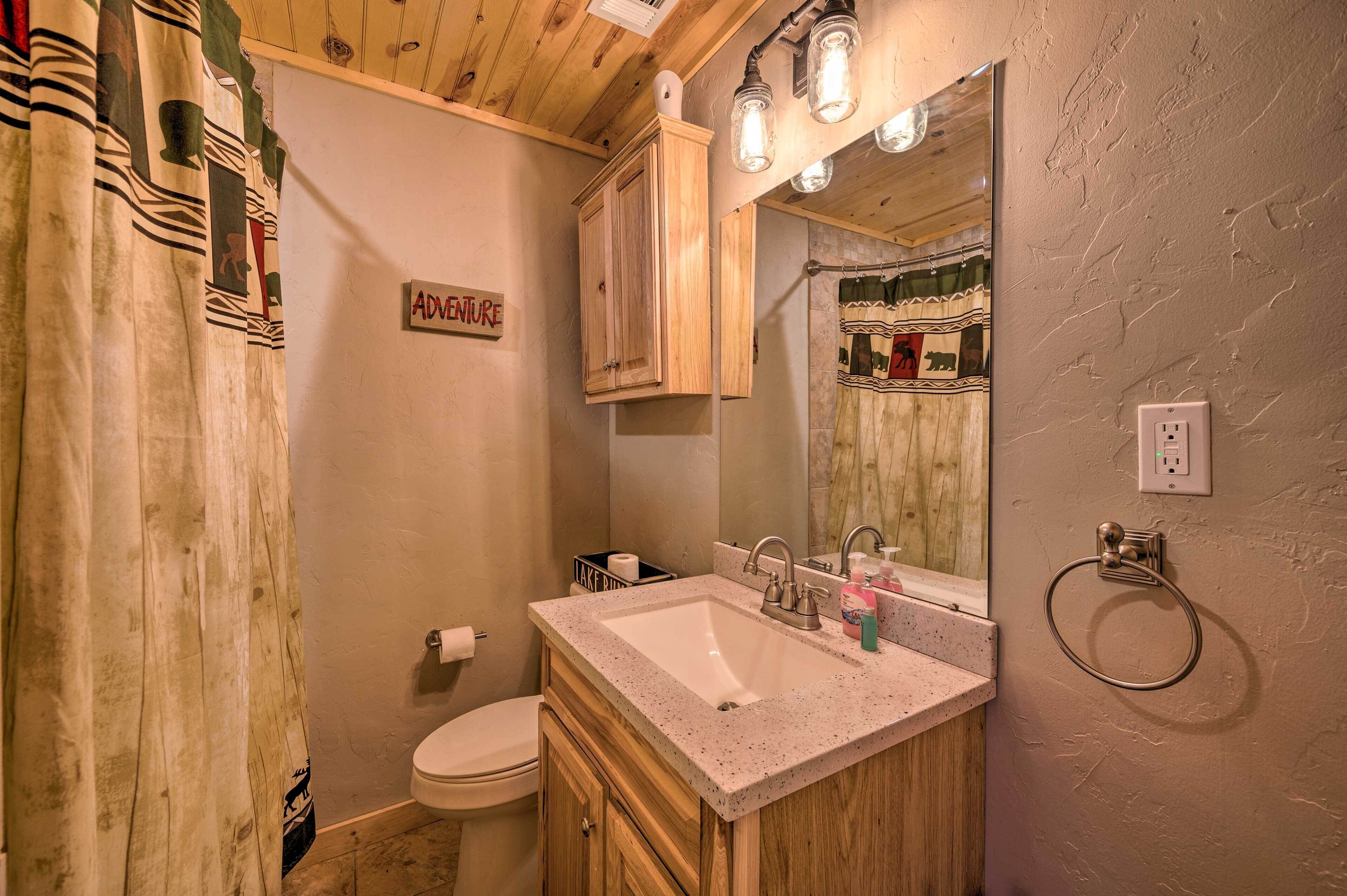 A bathroom with a wooden vanity, a sink, and a toilet. There is a sign on the wall that reads "ADVENTURE".