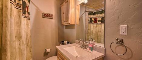 A bathroom with a wooden vanity, a sink, and a toilet. There is a sign on the wall that reads "ADVENTURE".