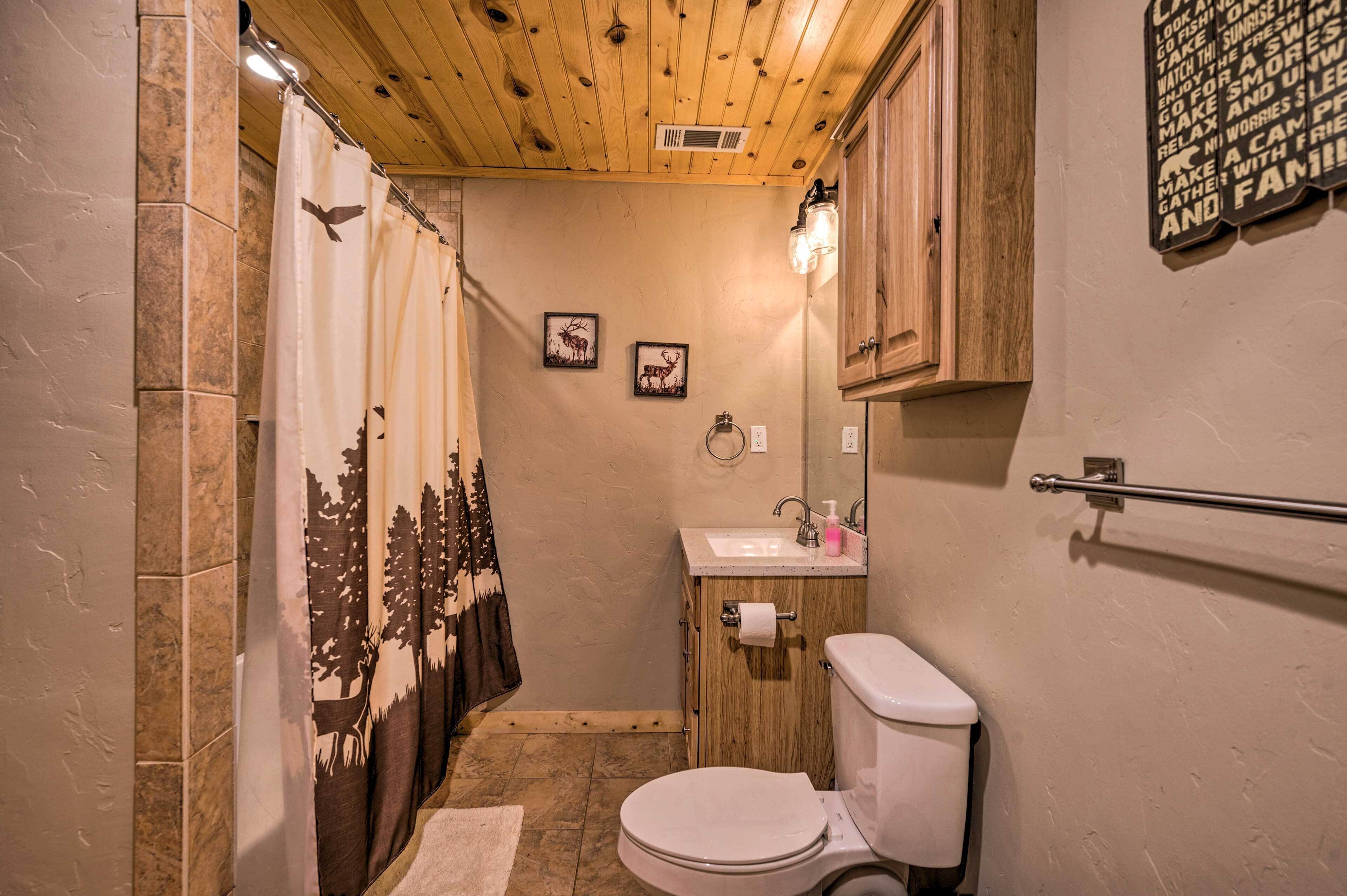 Une petite salle de bain avec un rideau de douche, des toilettes, un lavabo et un miroir.