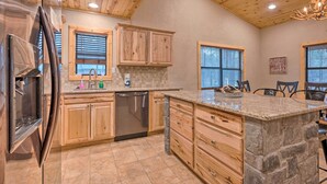A kitchen with wooden cabinets, a stone island, and a dishwasher. - Cabin w/ Hot Tub & Grill - 6 Mi to Broken Bow Lake (Broken Bow)