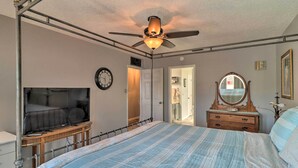 Ein Schlafzimmer mit Bett, Deckenventilator, Fernseher, Kommode und Spiegel.