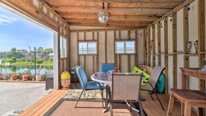 Eine Holzterrasse mit Tisch und Stühlen, einer hängenden Discokugel und Blick auf ein Gewässer.