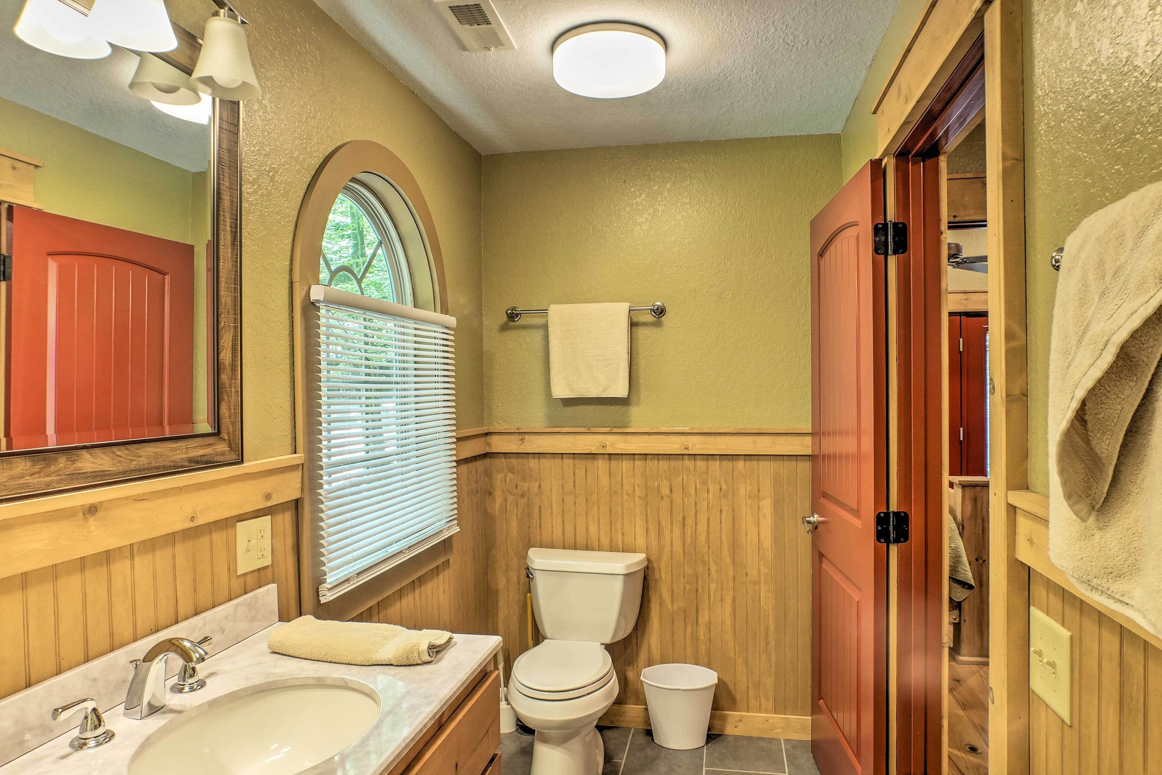 Une salle de bain avec un meuble-lavabo en bois, un lavabo blanc, des toilettes et un miroir.