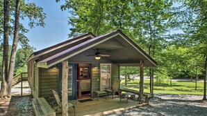 A rustic cabin with a covered porch, a dining area, and a kitchen. - The Treehouse at Kudzu Cove Cabins Resort (Guntersville)