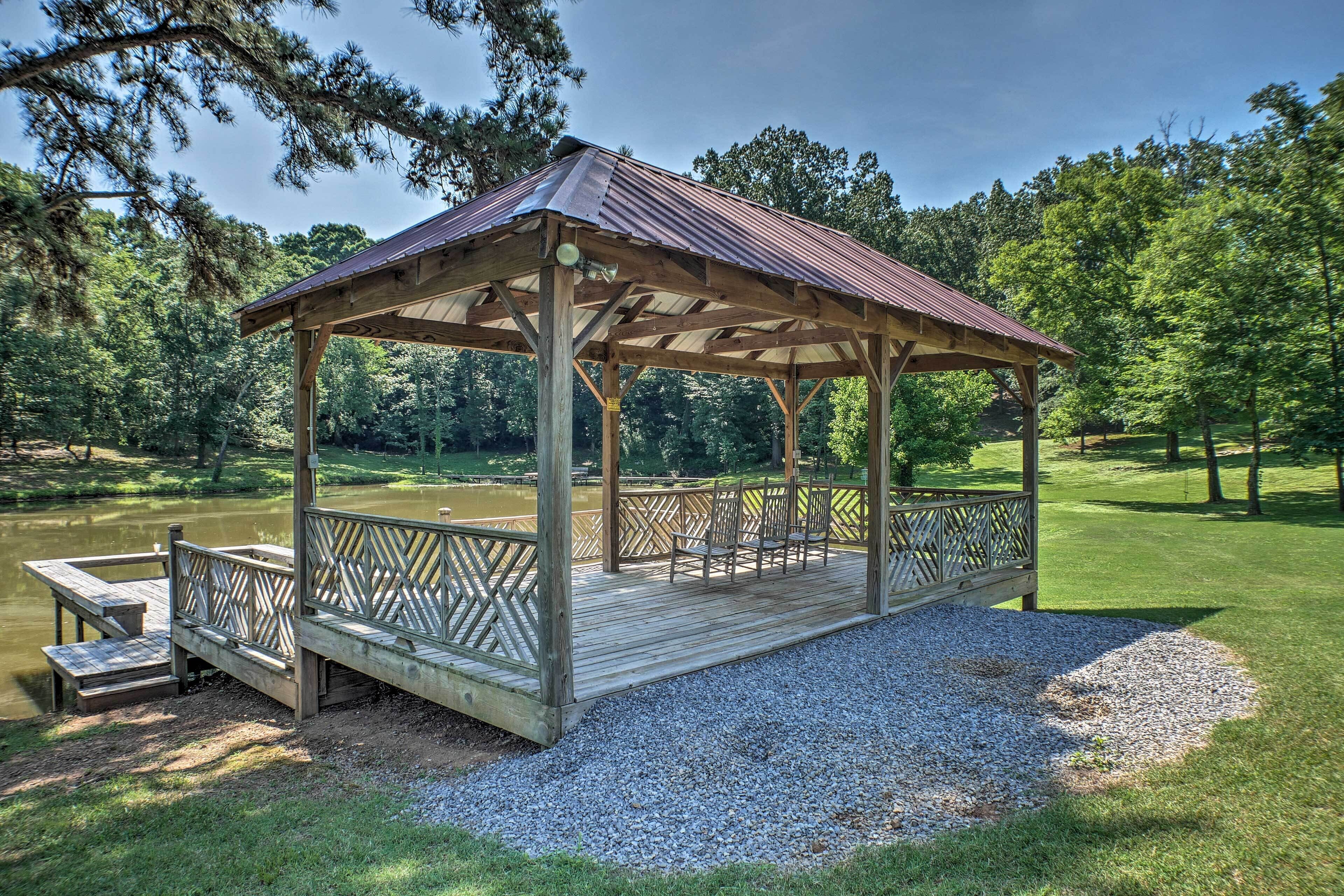 A wooden gazebo with a metal roof, a wooden deck, and a bench.