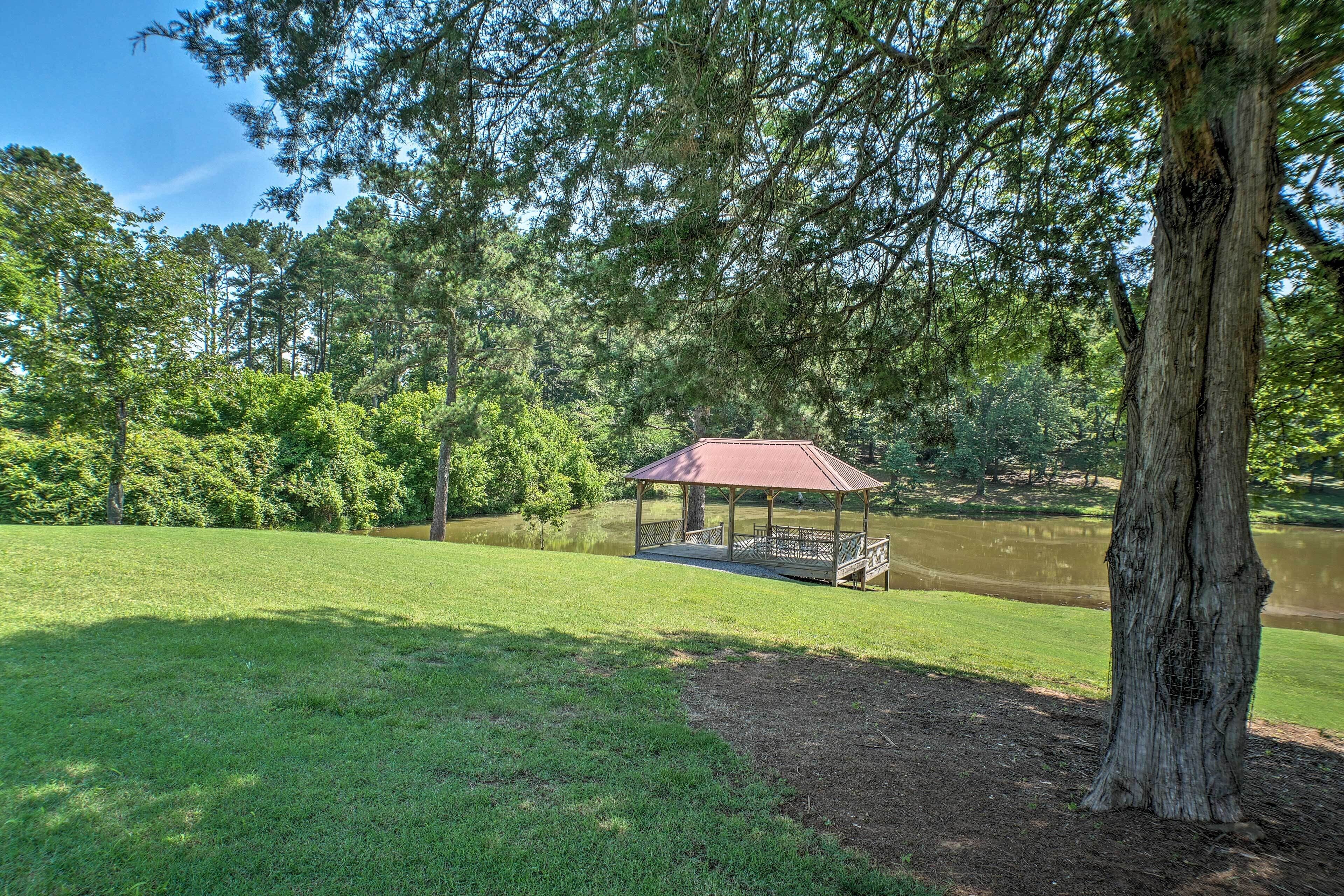 Ein Gazebo mit rotem Dach bietet Blick auf einen See, umgeben von üppigem Grün und Bäumen.