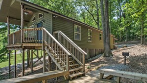 A cabin with a wooden deck, a staircase, and a bench. - The Treehouse at Kudzu Cove Cabins Resort (Guntersville)