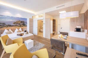 A modern hotel room with a large bed, a dining area, and a bathroom. - PM PremiumAPART Strassgang (Graz)