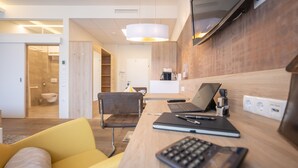 A modern hotel room with a wooden desk, a laptop, a notebook, and a yellow armchair. - PM PremiumAPART Strassgang (Graz)