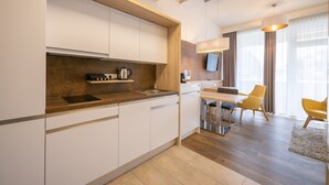 A modern kitchen with white cabinets, a wooden countertop, and a dining area with yellow chairs and a table. - PM PremiumAPART Strassgang (Graz)