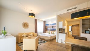 A modern hotel room with a sofa, a bed, a dining area, and a kitchen. - PM PremiumAPART Strassgang (Graz)