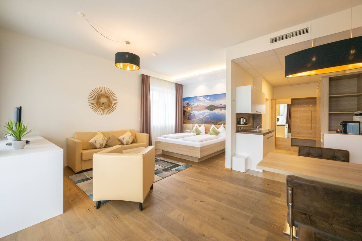Una habitación de hotel moderna con sofá, cama, zona de comedor y cocina.