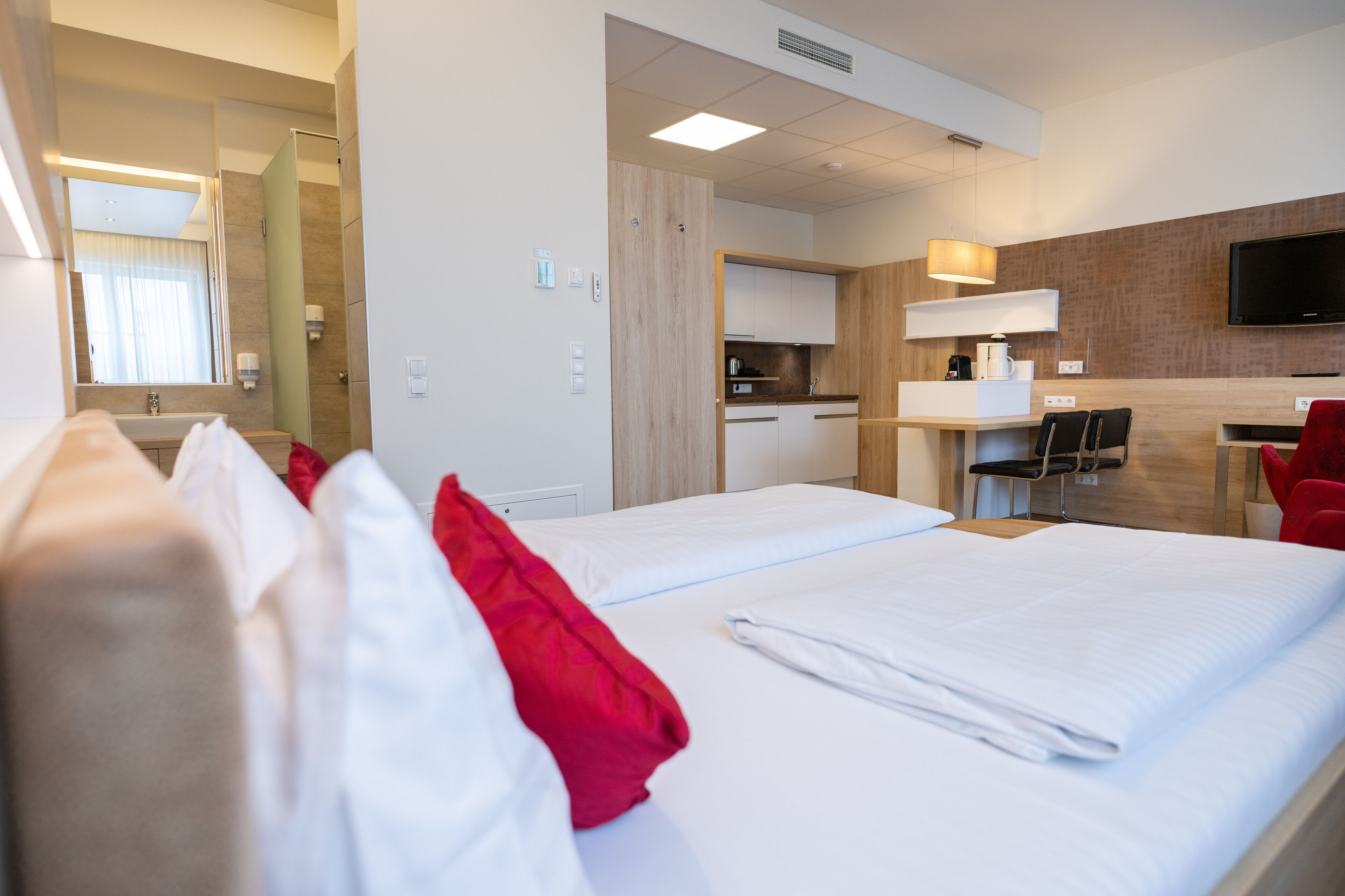 Une chambre d’hôtel comprenant un lit, un bureau, une chaise, une télévision et une salle de bain.