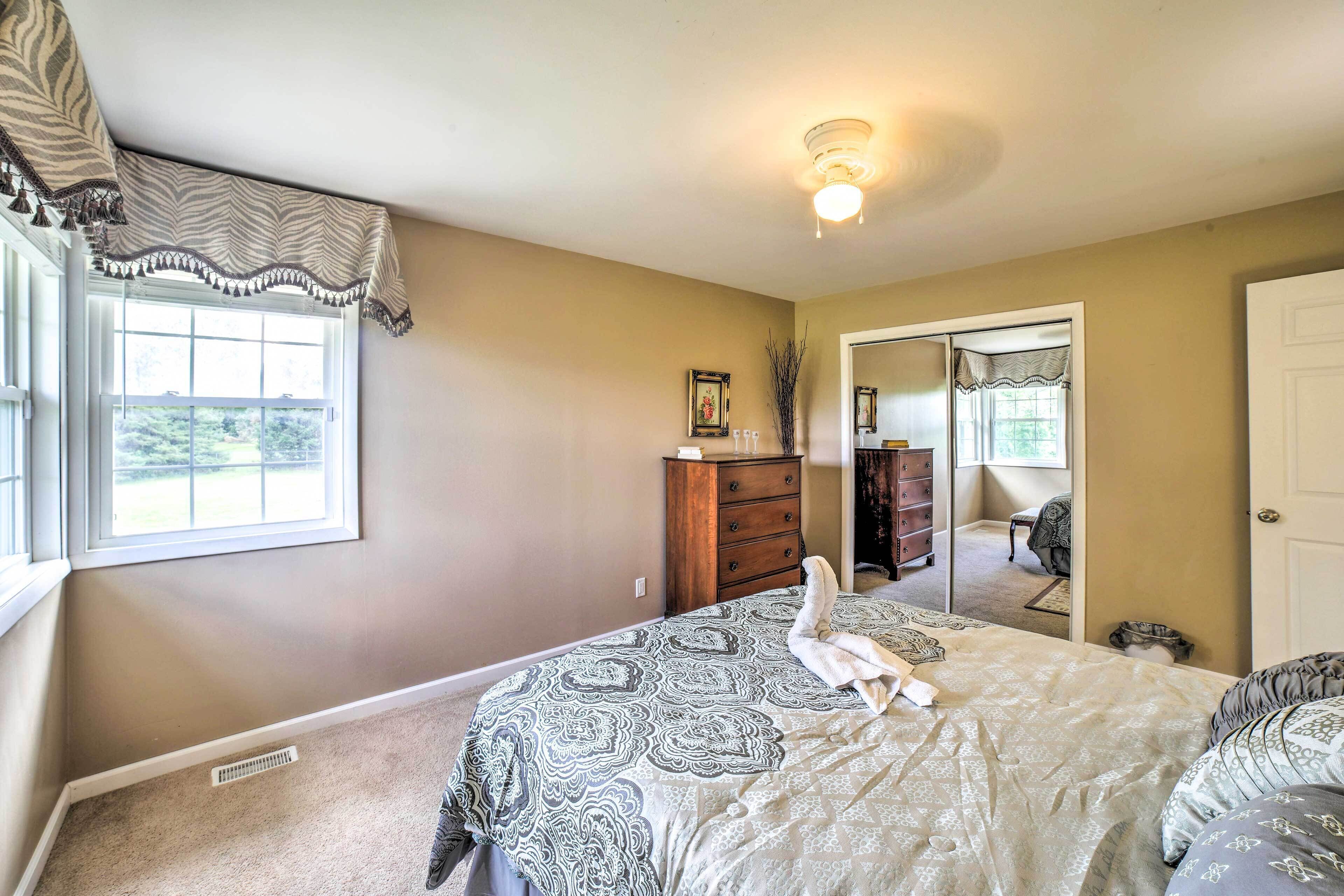 A bedroom with a large bed, a dresser, a mirror, and a window.